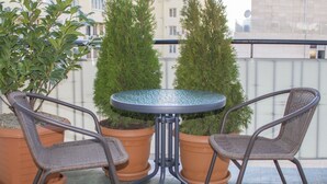A small outdoor seating area with two wicker chairs and a glass-top table, surrounded by potted plants. - Tbilisi Center Private 4-room Apartment (Dzveli Tbilisi)