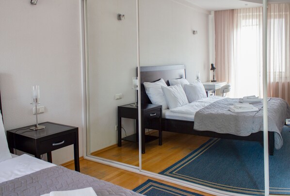 A hotel room with a bed, bedside table, and a mirror.