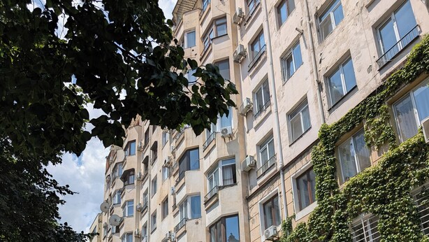 A multi-story building with balconies, satellite dishes, and a storefront with a blue awning. - Tbilisi Center Private 4-room Apartment (Dzveli Tbilisi)