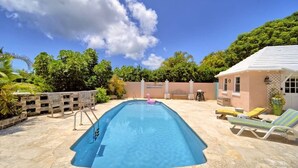 A rectangular swimming pool with a diving board, surrounded by stone tiles and outdoor furniture. - Cottage Priv. Pool & Tennis Beach 5 min Central (Paget)