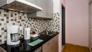A kitchen with a black countertop, a Bosch coffee maker, a toaster, and a sink. - Lourdas bay great view - Studio Maria (Kefalonia)