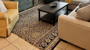 Sala de estar com televisão, sofá, mesa de centro e objetos decorativos na parede.