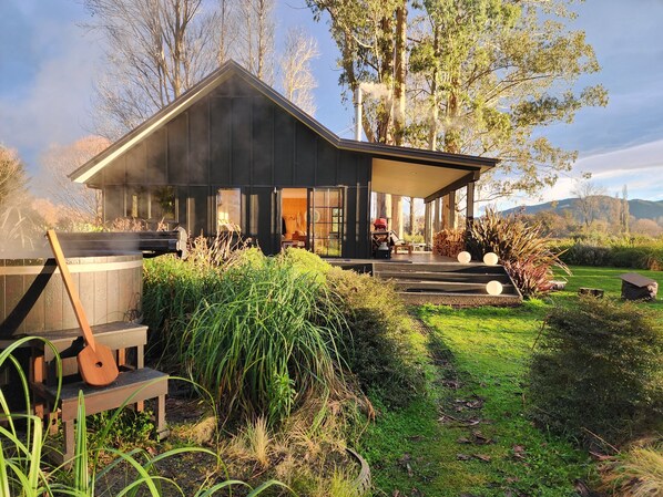 Una casa moderna con porche cubierto, jacuzzi y zona de barbacoa.