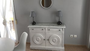 Une coiffeuse blanche avec deux lampes, un miroir et un plan de travail en marbre.