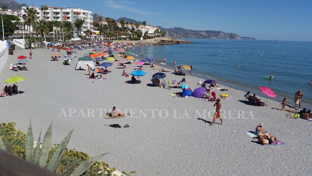 Une plage où l’on peut se détendre au soleil et se baigner, avec des parasols et une vue dégagée sur la mer.
