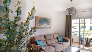 Un salon moderne avec un canapé, une table basse et une grande fenêtre donnant sur l’extérieur.