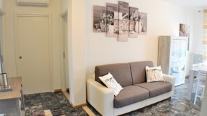 A modern living room with a sofa, a coffee table, and a wall-mounted artwork. - Entire apartment CASA FELICE 9 Places Free Parking and Free Wi-Fi Included (Venezia)
