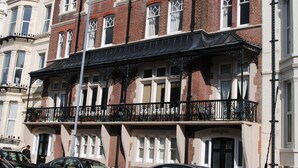 Un edificio de varios pisos con un toldo negro sobre la entrada, un letrero que dice 