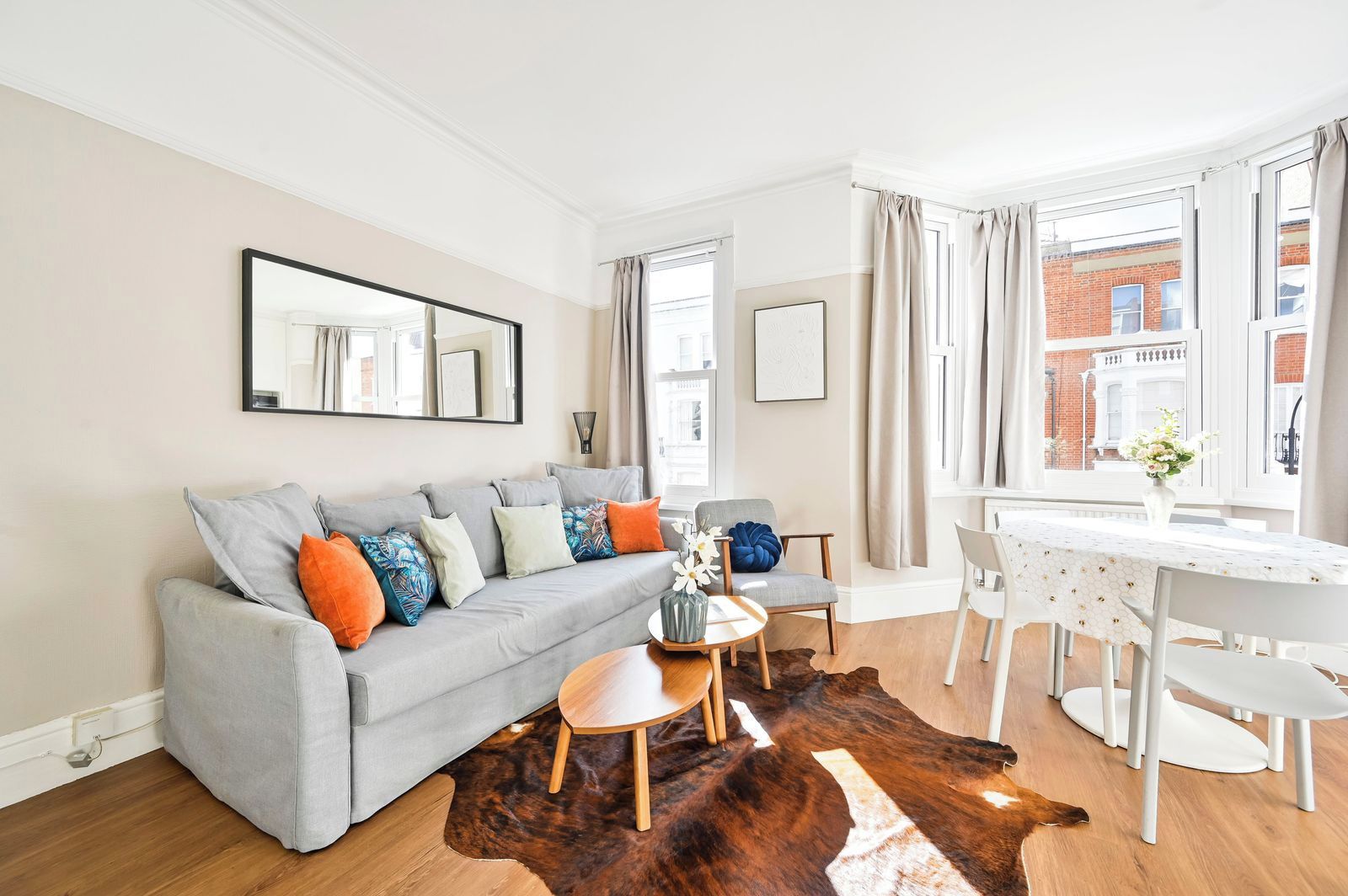 A modern living room with a grey sofa, a coffee table, and a dining area with a white table and chairs.