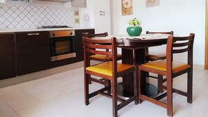 Une cuisine moderne avec un coin repas, comprenant une cuisinière, un four, des placards et une table à manger avec des chaises.