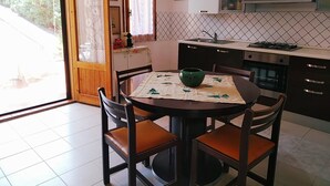 Une cuisine équipée d’une table à manger, de chaises, d’une cuisinière et d’un évier.