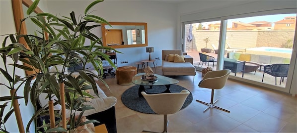 Una sala de estar moderna con un sofá, sillones, una mesita de centro y una planta grande en maceta.