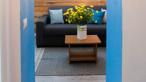 Una habitación con una pared azul decorativa, techo de madera, sofá negro con cojines azules, una mesa de centro de madera y un globo azul colgante.