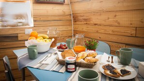 Una mesa de desayuno con diversos alimentos, como pan, pasteles, frutas y bebidas.
