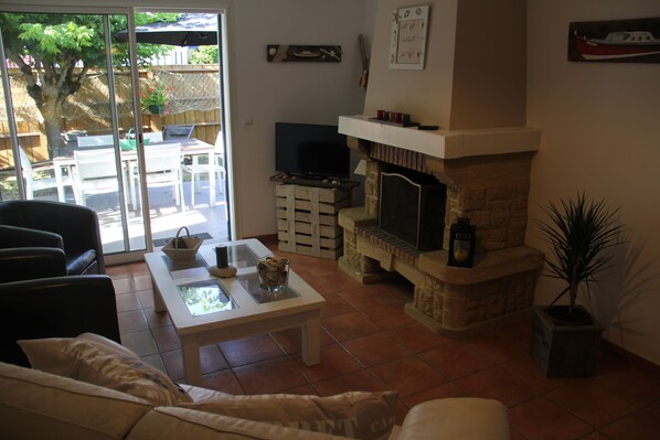 A living room with a fireplace, a television, and a dining area with outdoor seating.