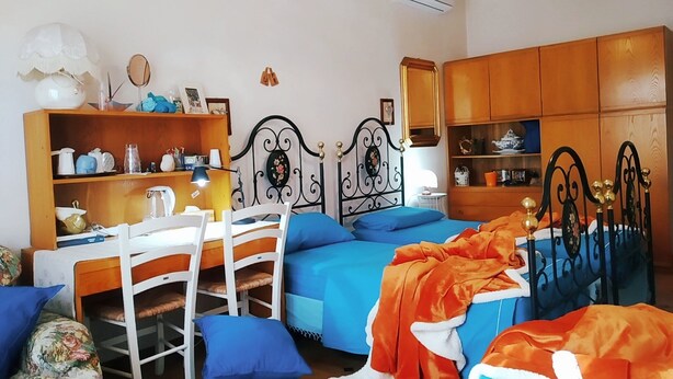 A bedroom with two beds, a desk, and a chair. There is a shelf with various items and a hanging light fixture. - Beautiful room in the center of Milis!!!<br><br> ♥ 10 minutes from the sea ♥ (Milis)