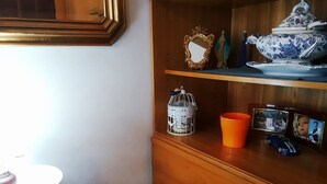 A wooden shelf with decorative items including a blue and white porcelain set, a white birdcage, and framed photographs. - Beautiful room in the center of Milis!!!<br><br> ♥ 10 minutes from the sea ♥ (Milis)