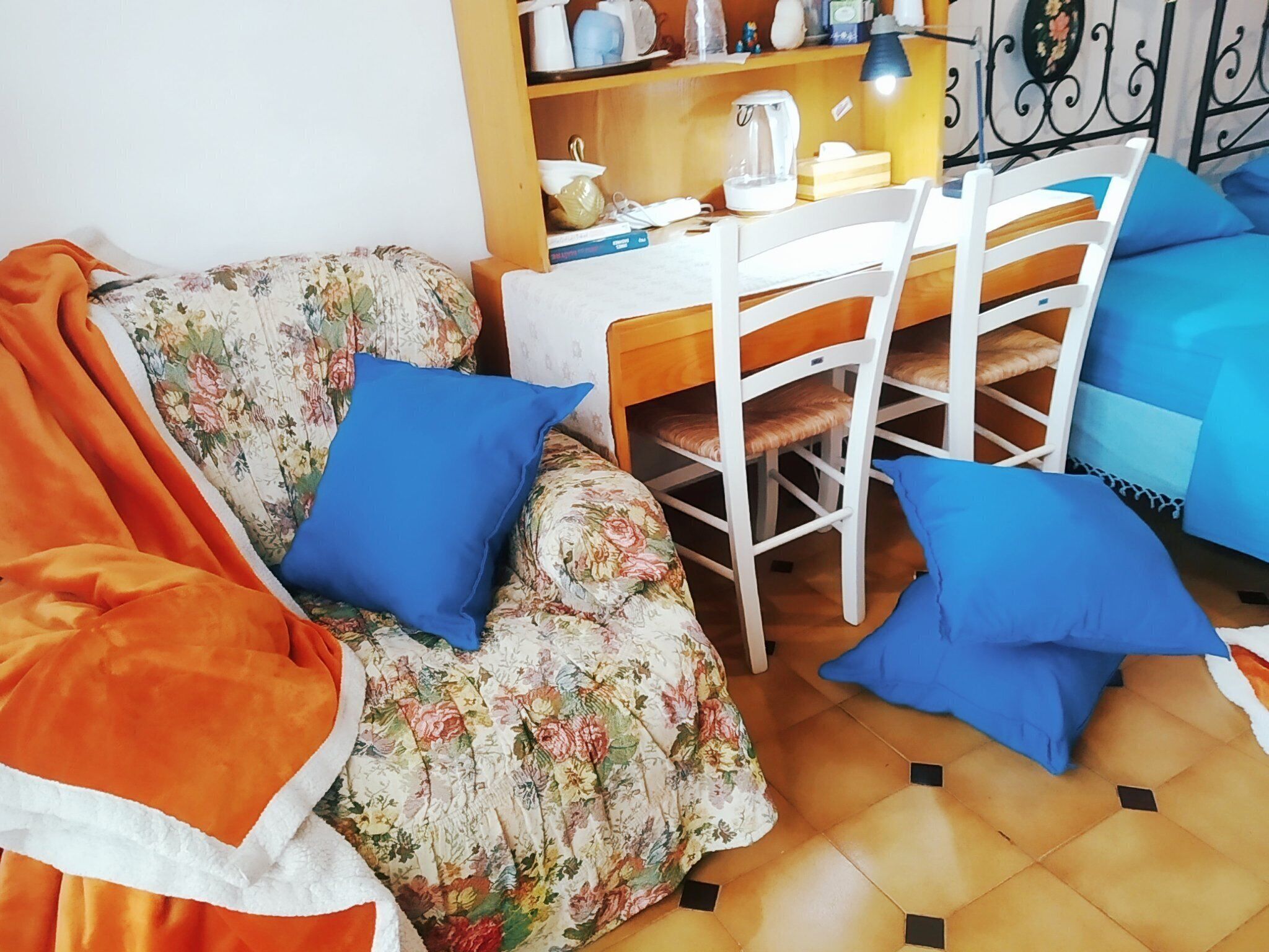 Un salon chaleureux avec un canapé à motifs floraux, une table à manger en bois et des coussins bleus.