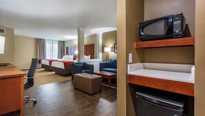 Une chambre d’hôtel équipée d’un lit, de deux canapés, d’un bureau, d’un four à micro-ondes et d’un mini-réfrigérateur.