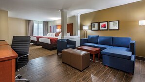 Une chambre d’hôtel avec un lit, deux canapés, un bureau et une chaise.