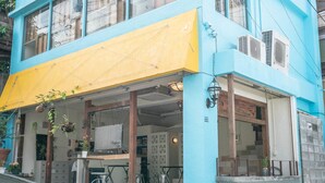 A two-story building with a blue and yellow facade, large windows, and a balcony.