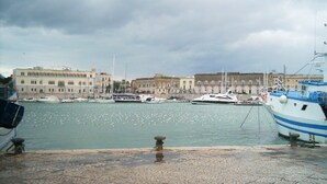 A marina with boats docked, a waterfront promenade, and buildings in the background. - DWELLING SIMONA THE CATHEDRAL WITHIN WALKING DISTANCE VACATION HOME TRANI ITALY (Trani)