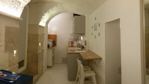 A narrow hallway with a small kitchen area, a dining table with chairs, and a refrigerator. - DWELLING SIMONA THE CATHEDRAL WITHIN WALKING DISTANCE VACATION HOME TRANI ITALY (Trani)