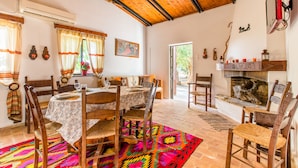 A dining area with a wooden table and chairs, a colorful rug, and a fireplace. - Villa Aadonis in the sea (Chania kolibari)