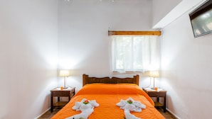 A hotel room with a large bed, two bedside tables, a window with curtains, and a flat-screen TV mounted on the wall. - Villa Aadonis in the sea (Chania kolibari)