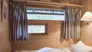 A wooden cabin room with a bed, a window with curtains, and a lamp. - 4 bedroom beautiful home in Tvedestrand (Tvedestrand)