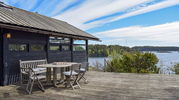 A wooden cabin with a deck, a table, and chairs. - 4 bedroom beautiful home in Tvedestrand (Tvedestrand)