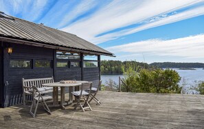 A wooden cabin with a deck, a table, and chairs.