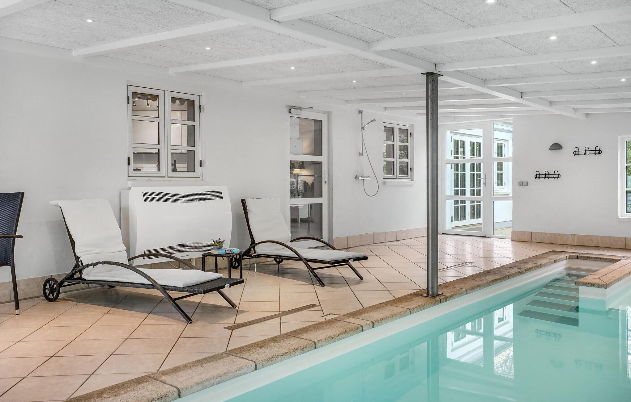 Zona de piscina con dos sillas de descanso, un ventilador de techo y un calentador de agua.