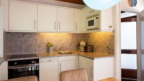 A compact kitchen with white cabinets, a built-in microwave, a coffee maker, and a dishwasher. - Gravenhof 12 bungalow on holiday park in forest and dune area (Burgh-Haamstede)