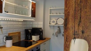Eine kleine Küche mit weißen Schränken, einer Holz Arbeitsplatte, einem Einbauofen und einer Kaffeemaschine.