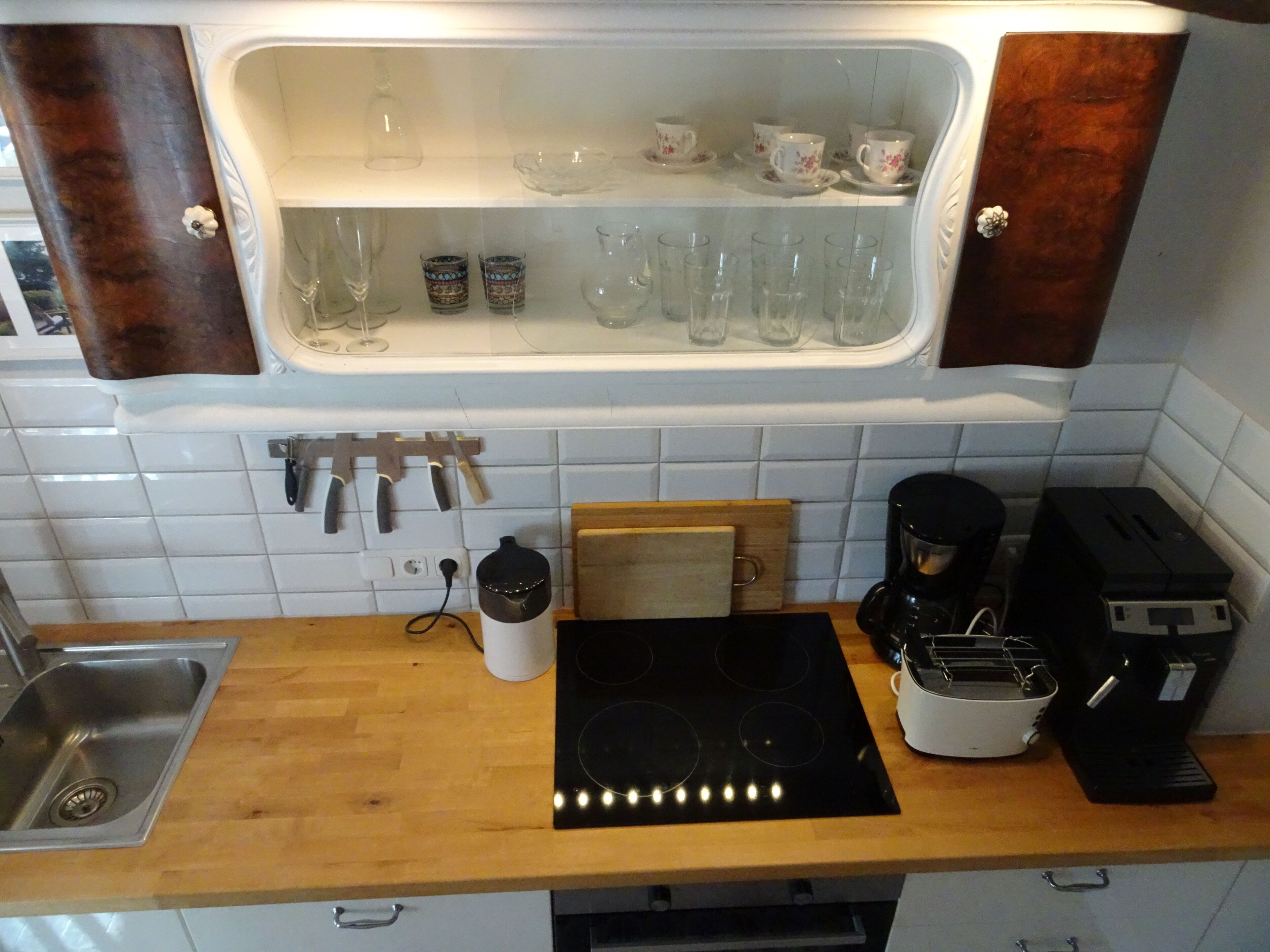 Een keuken met een inbouwkastje met glazen en een koffiezetapparaat.