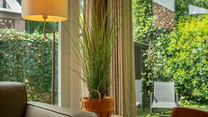 Une pièce avec vue sur un jardin, un panier en bois contenant des plantes vertes et une lampe.