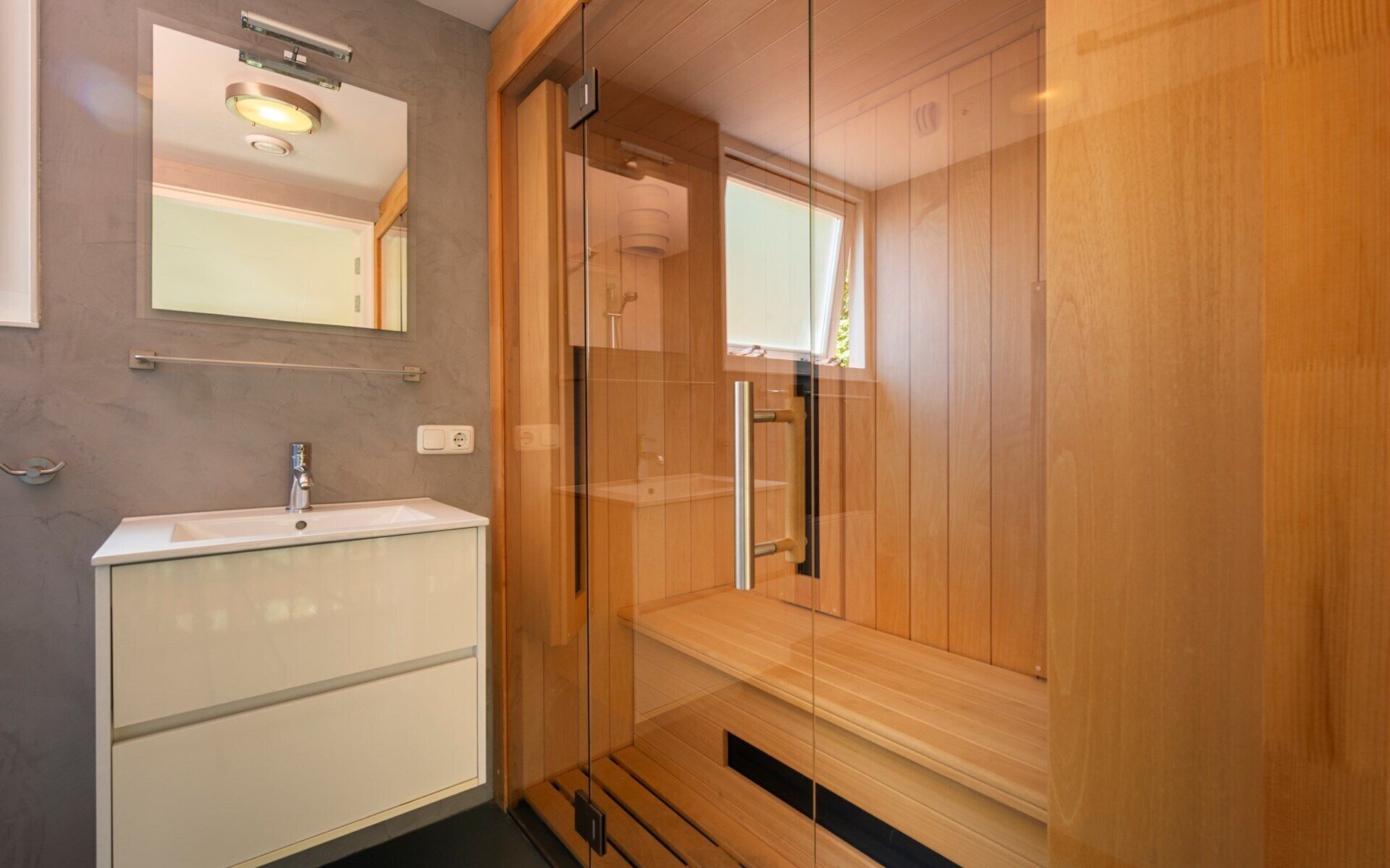 Une salle de bain moderne avec un meuble-lavabo en bois, un miroir et une cabine de douche en verre.