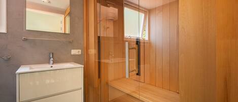 Une salle de bain moderne avec un meuble-lavabo en bois, un miroir et une cabine de douche en verre.