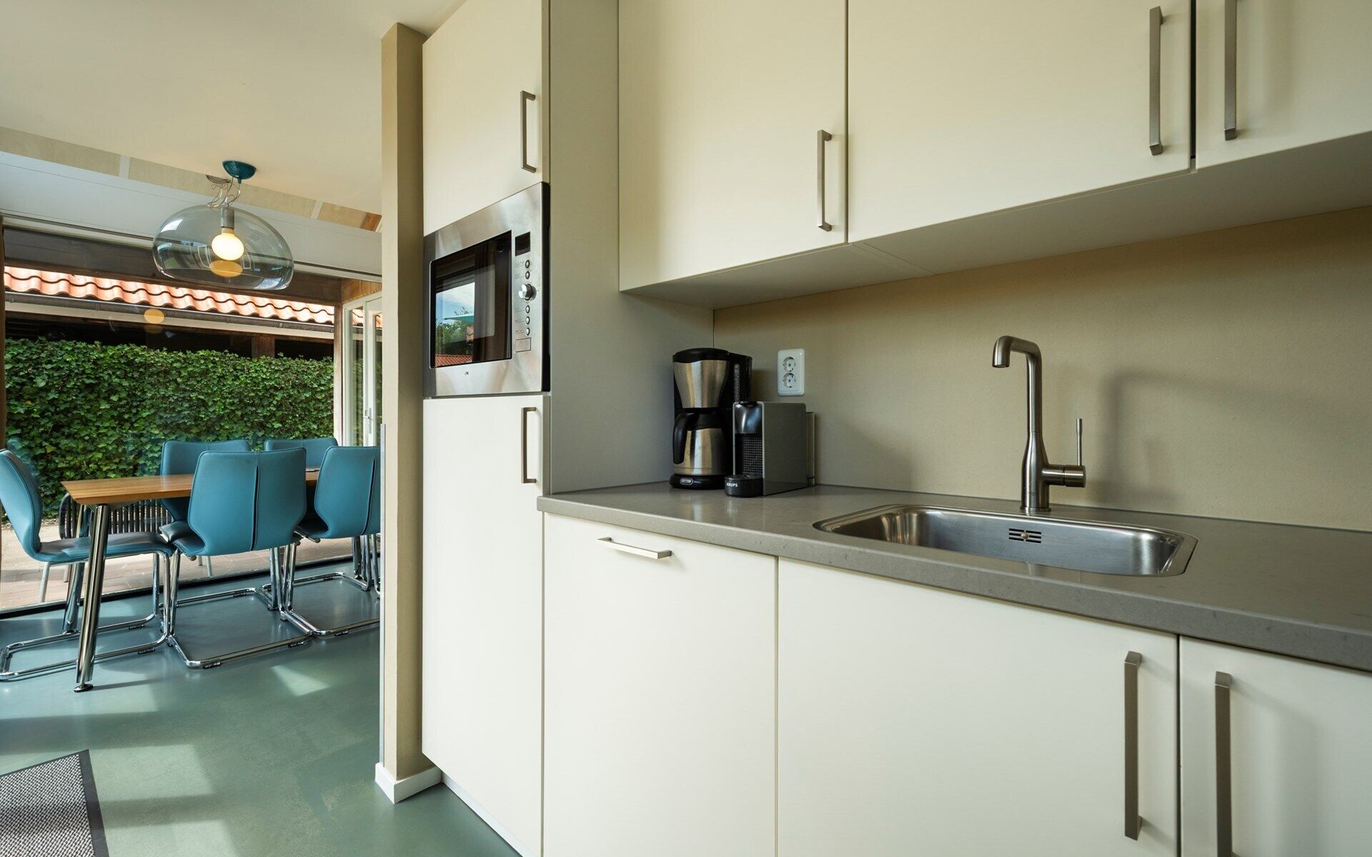 Una cucina moderna con forno a microonde integrato, macchina del caffè e lavello in acciaio inossidabile.