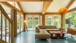 Une pièce spacieuse avec un grand canapé d’angle, une petite table et une lampe suspendue.