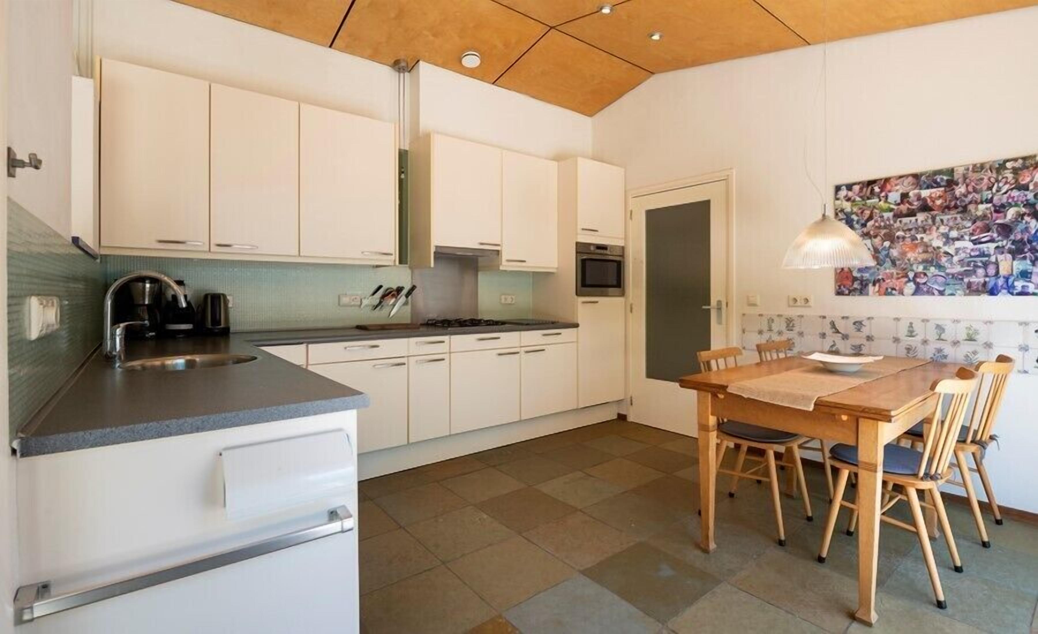 A compact kitchen with white cabinets, a built-in oven, and a dining area with a wooden table and chairs.