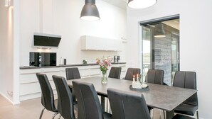 A modern dining area with a dark wooden table, black chairs, and pendant lighting.