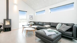 A modern living room with a black leather sofa, a round coffee table, and a fireplace.