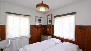 Une chambre à coucher avec un lit, une table de chevet, un miroir et une fenêtre.