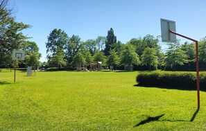 A park with a basketball court, playground, and trees. - Amazing home in Bruinisse with kitchen (Bruinisse)
