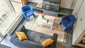 A modern living room with a grey sofa, blue armchairs, a white coffee table, and patterned rugs. - Amazing home in Bruinisse with kitchen (Bruinisse)