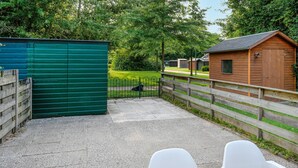 A fenced outdoor area with a green shed, a wooden building, and a paved path. - Amazing home in Bruinisse with kitchen (Bruinisse)
