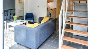 A modern living space with a sofa, a chair, a small table, and a staircase. - Amazing home in Bruinisse with kitchen (Bruinisse)