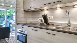 A modern kitchen with stainless steel appliances, a built-in oven, and a large window overlooking a deck area. - Amazing home in Bruinisse with kitchen (Bruinisse)